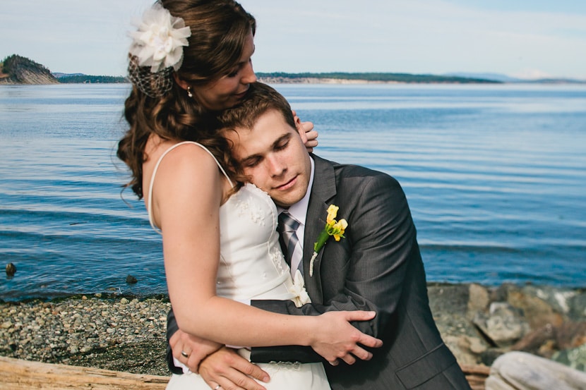 bride and groom hug in front of ocean at island view beach