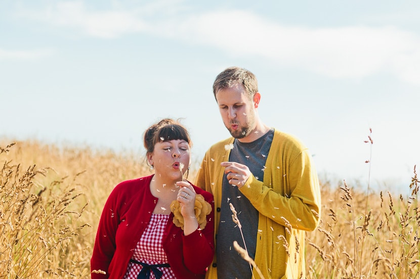 couple blowing dandelion dust at engagement session