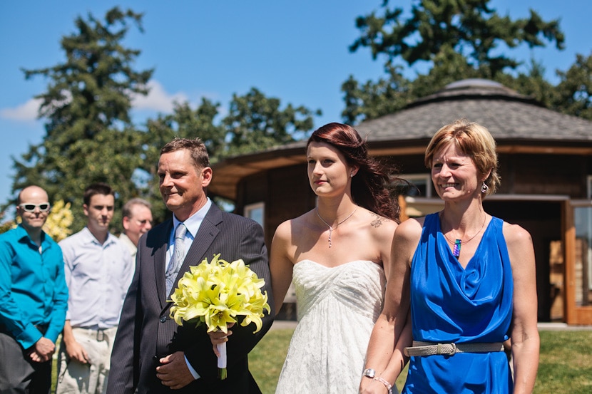 father and mother walk bride down aisle at wedding ceremony