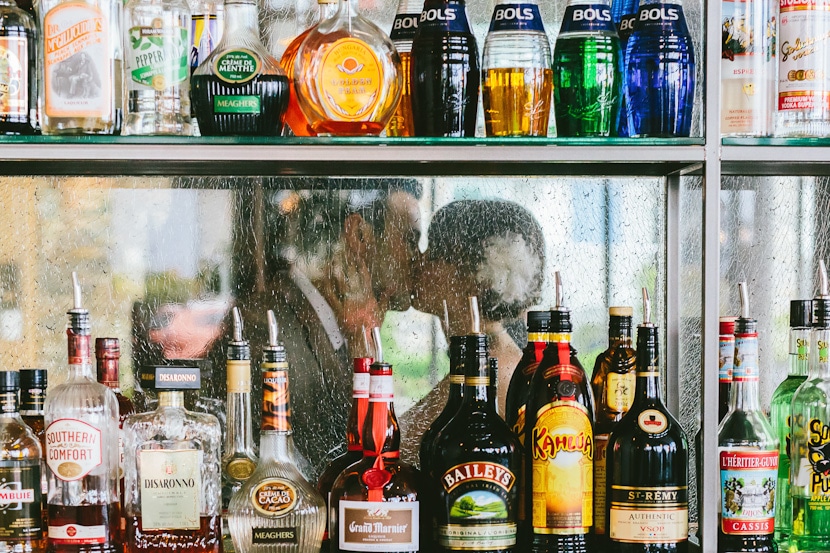 creative wedding portrait through liquor bottle shelves at bar