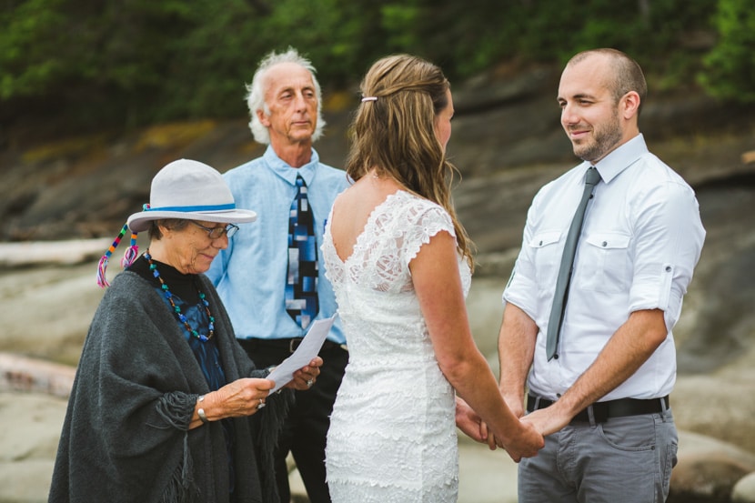 Outdoor wedding ceremony on the beach - the bride in a lace gown and the groom casually clad in a tie and rolled up sleeves