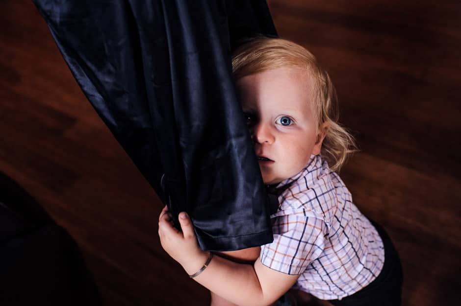 little boy hiding behind mother's legs