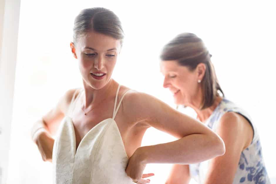 mother helping bride with dress