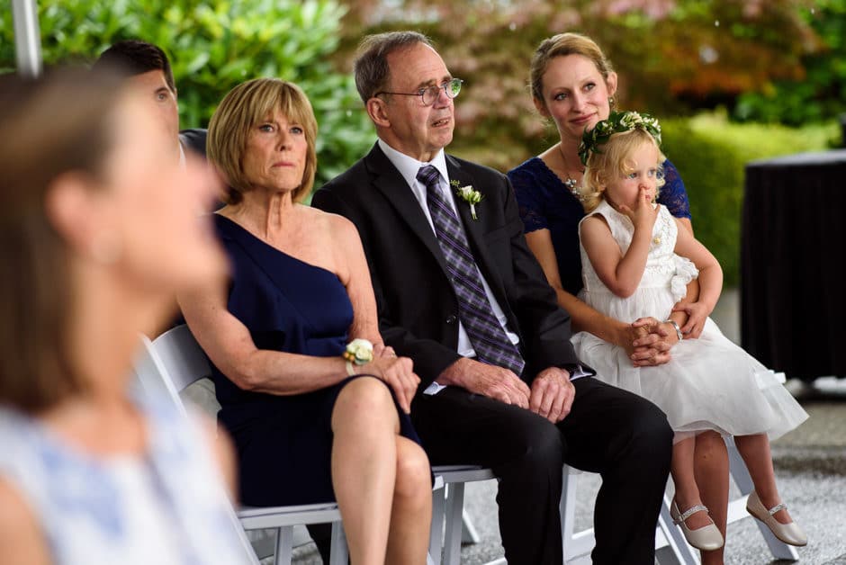 flower girl picking nose as groom's family watches ceremony