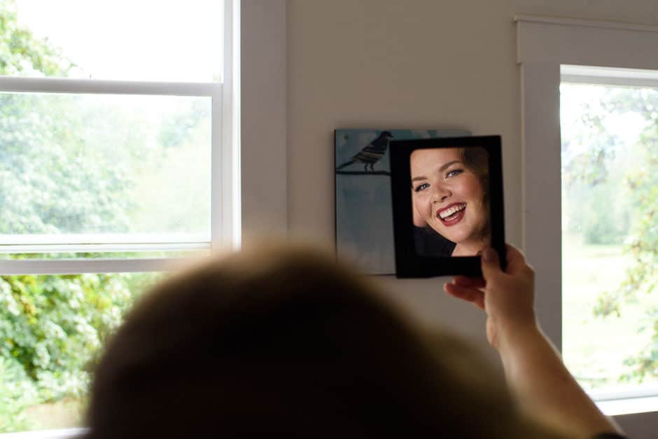 bride smiling at makeup in mirror