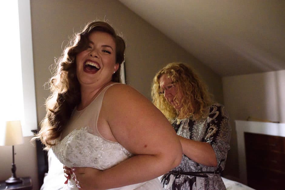 bride laughing putting on dress