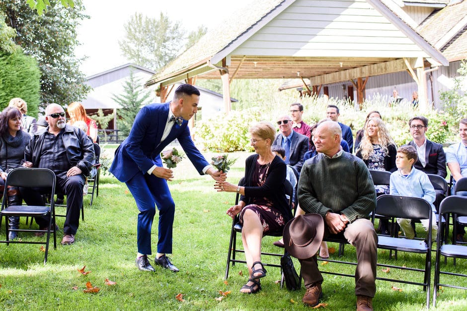 bridesman handing bouquet to mothers